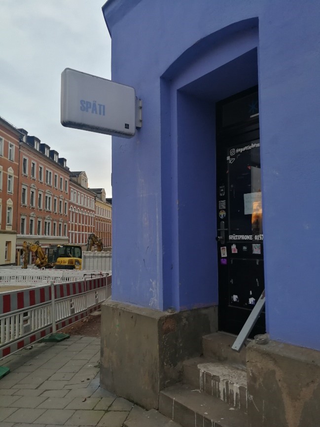 Eckhaus in Blau mit Eingangstür und Späti-Schild